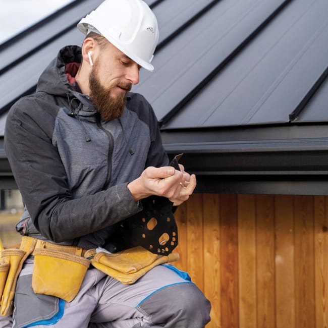 Young handyman working on gutter installation with hammer.
