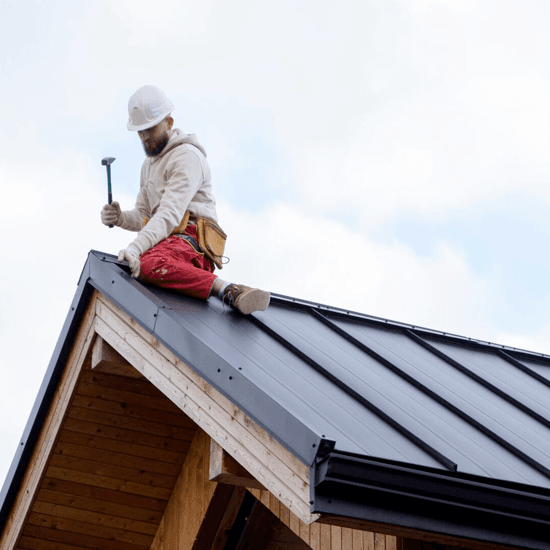 The-Real-Cost-of-Neglecting-Your-Roof- Full shot of a worker performing roof maintenance on a metal roof
